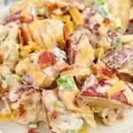 Loaded potato salad in ceramic bowl with steak and cheddar